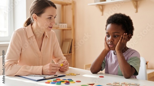 Education: Teacher supports disengaged Black child during an individual phonics learning activity
