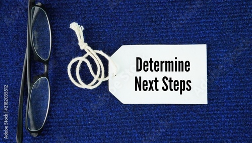 Cuadro en lienzo Glasses and paper tags with the words Determine Next Steps