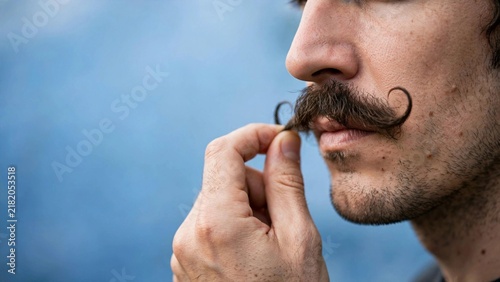 Man with a mustache wearing a blue awareness ribbon, promoting Movember and men's health awareness