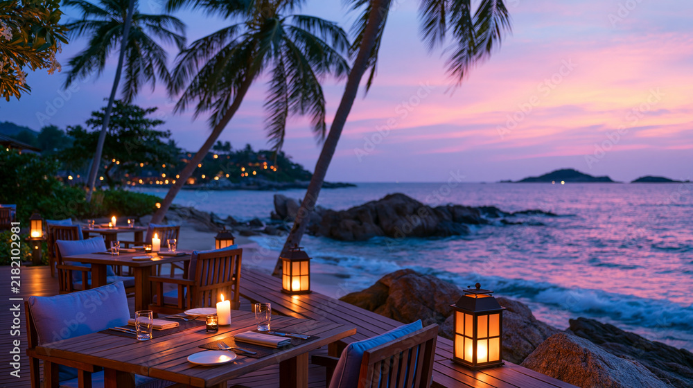 Fototapeta premium Luxury beachfront dining experience with wooden tables and chairs set on a deck overlooking purple sunset and rocky sea view.