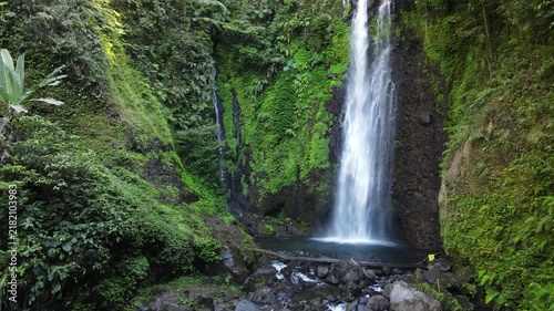 Aerial footage of Cidadap Waterfall Surrounded by Wild Banana Trees and Dense Tropical Vegetation During Morning in Indonesia. Forest and the Flowing Cascade Create Vibrant Nature in the Wilderness.