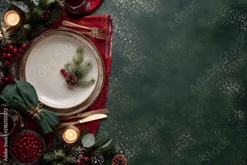 A table set for a festive meal, seen from above, cutlery and greenery, photo, classic deep green, cranberry red and cream