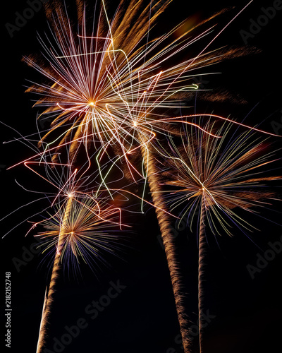 Close up vibrant color photo of beautiful fireworks and light trails against a dark black night sky with copy space.