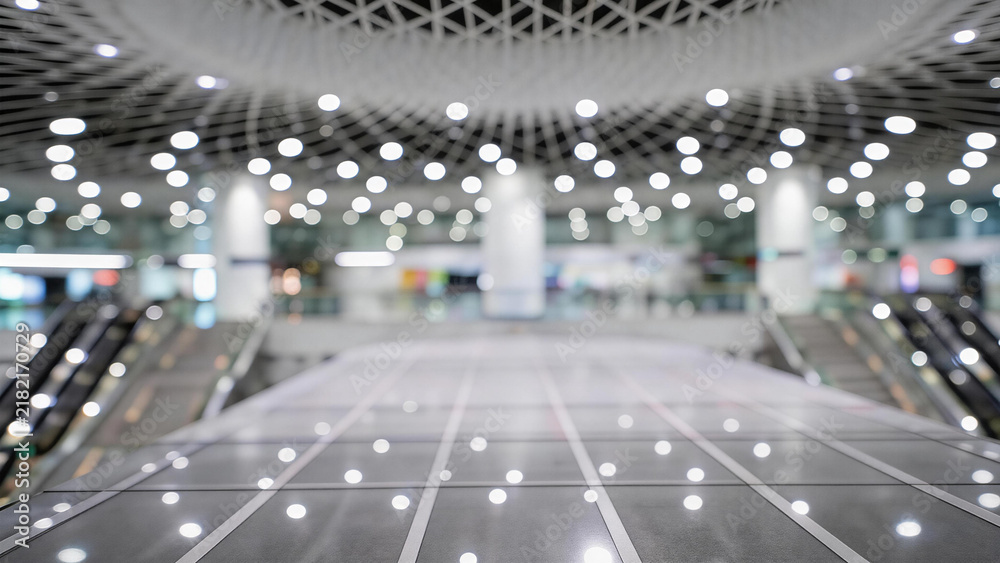 Obraz premium A spacious, modern empty indoor public area with escalators, tiled floor, and bright ceiling lights. Clean and unoccupied architectural space.