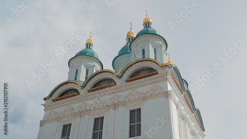 Tapety artystyczne Low angle view of ornate white church featuring teal domes with gold crosses. Soft daylight highlights intricate stonework arched windows against pale sky