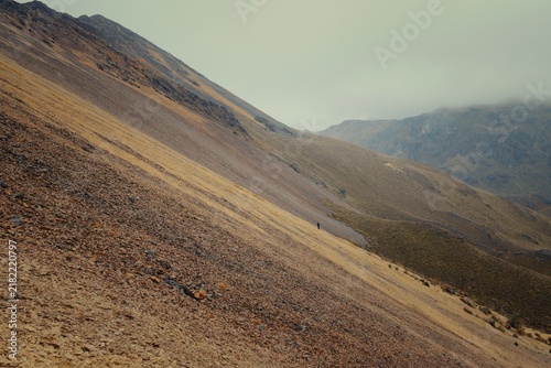 Hiker walking on a rocky mountain trail in Cajas National Park Ecuador
