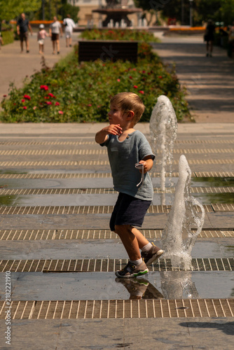 Young Boy Walking Between Outdoor Fountain Water Jets