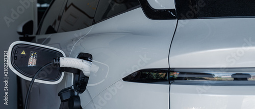 Foto Person plugging in EV charging cable to white electric vehicle for sustainable energy transport