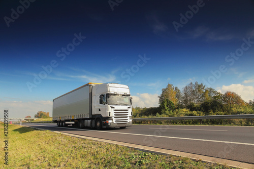 A truck on a highway drives through a wide landscape, transporting goods