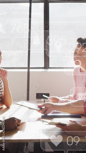 Diverse team discusses under floating social media icon, symbolizing tech integration.
