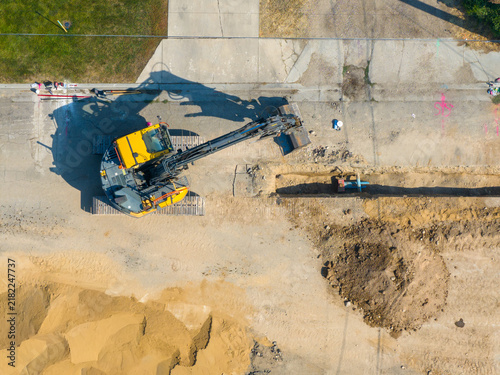 Top-down shot of yellow excavator moving dirt during site work
