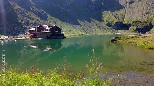 Scenic Balea Lake and mountain lodge reflected beneath steep Carpathian slopes in Romania