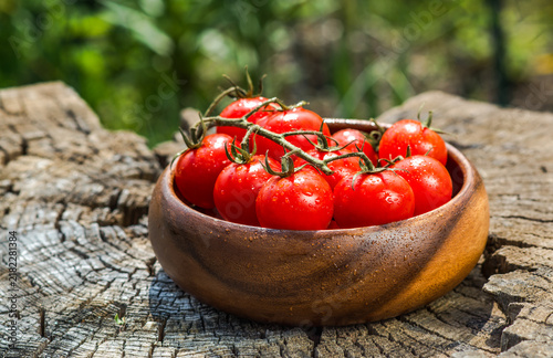 Cherry tomatoes in plate on old wooden surface, space for text.
