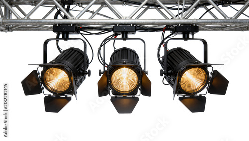 Принти на полотні Three black stage spotlights with barn doors illuminated with warm yellow light,