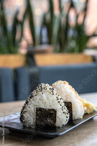 Onigiri or Japanese rice triangle served on the wooden tabletop in the cafe. Kimbab or gimbap - Korean rice triangle. Japanese onigiri sushi. Korean Samgak-gimbap. Selective focus.