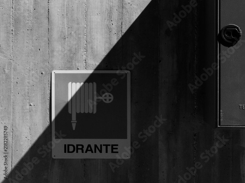 Idrante, antincendio, estintore, scritta su cartello quadrato. Sfondo geometrico di elementi, luci ed ombre in bianco e nero. Diagonale.