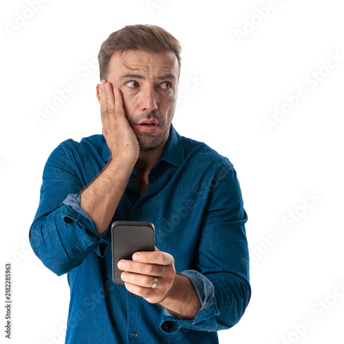 Worried middle aged man holding phone looking side