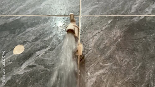 Water Running From Plastic Tap Against Grey Marble Tile Wall