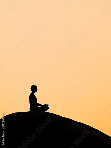 Silhouette of person meditating on a sand dune at sunset