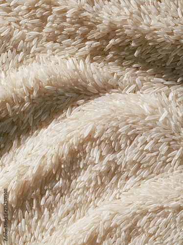 Close-up of a pile of white rice grains. the grains are arranged in a criss-cross pattern, creating a textured and organic appearance. the texture appears to be soft and fluffy, with a subtle sheen.
