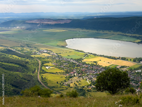 Panoramic vista of Hrhov village, railway, farmlands, and Hrhovské rybníky pond from the slopes of Slovak Karst, Slovakia.