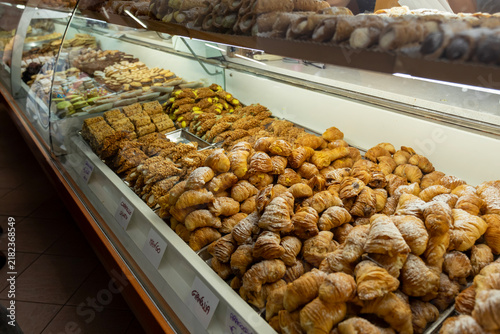 Fotografía A tempting window display of stacked Cannoli pastries in Sanremo, featuring classic, pistachio, and amaretto flavors, with handwritten price tags showcasing Italian street food