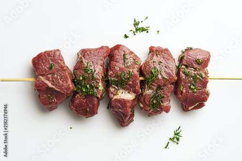 Raw beef meat skewer with herbs isolated on white background top view