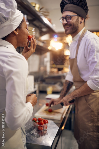 Cook in Professional Modern  kitchen, restaurant concept. Chef preparing tomatoes with colleague