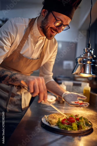 Cook in Professional Modern  kitchen, restaurant concept. chef decorating meal in dramatic lighted kitchen.