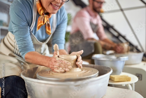 close up of woman wet hands making clay pot on wheel at pottery studio. Creative, hobby ,activities concept