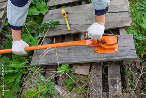 Fotografía Man using manual orange rebar bender to shape steel rod on construction site