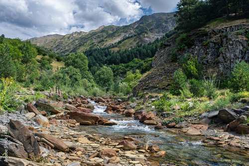 Senderismo por las montañas y valles del Valle de Aran en el Pririneo, caminando junto a un río alpino