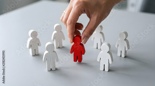 employee selection concept with hand choosing red wooden figure from a group