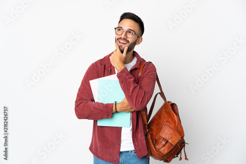 Young student man isolated on white background looking up while smiling