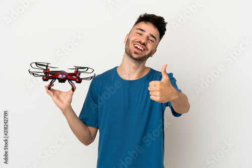 Obraz na płótnie Man holding a drone isolated on white background with thumbs up because somethin