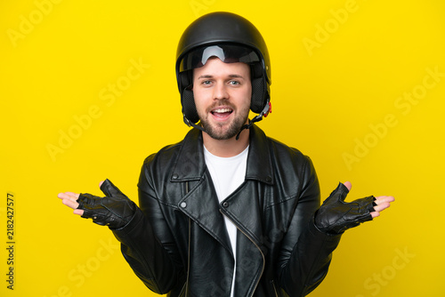 Fotografie Young caucasian man with a motorcycle helmet isolated on yellow background with