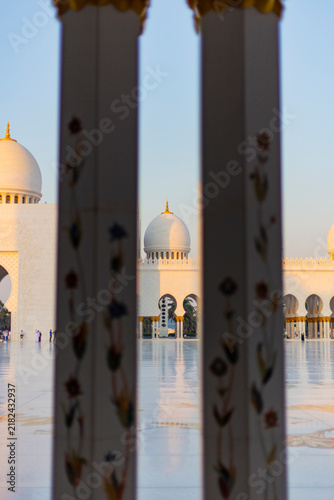 Arches and columns in a white marble building landmark Grand Mosque in Abu Dhabi at sunset