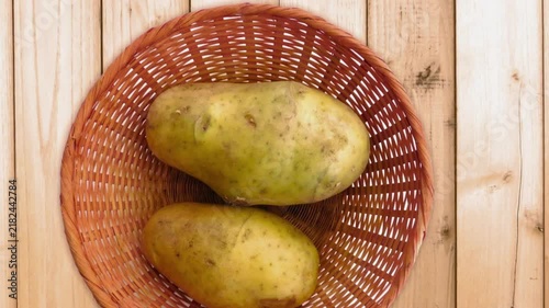 Fresh raw potatoes in wicker basket, organic whole potato tubers on wooden table, rustic farm harvest for cooking and food preparation