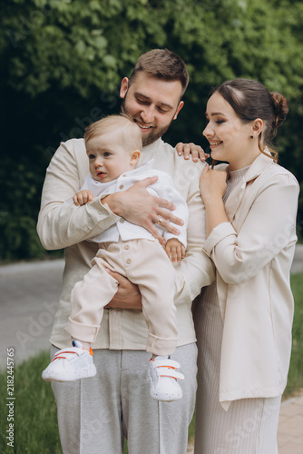 Картината върху платно Loving parents holding their young baby boy outdoors, sharing a moment of togeth