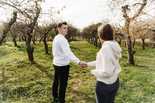 Cuadro en lienzo Young couple holding hands in an autumn orchard, with a softly...