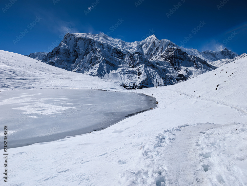 Fototapeta premium Frozen Ice Lake and Snow Covered Mountains in the Himalayas of Nepal