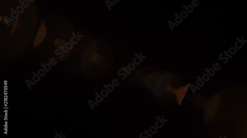 Golden Lens Flare radiating light with hexagonal bokeh during a dramatic cinematic transition over black
