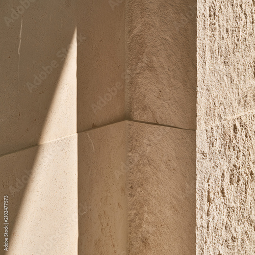 Sunlight and shadow on the corner of a smooth and rough limestone wall
