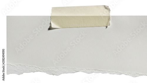 A piece of grey torn paper held up by a small strip of beige masking tape
