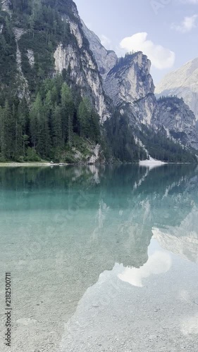 Sunrise view of Lake Braies: mountains reflected in calm morning water and traditional wooden boats along the shore, Dolomites, Italy. Iconic alpine landscape and popular travel destination.