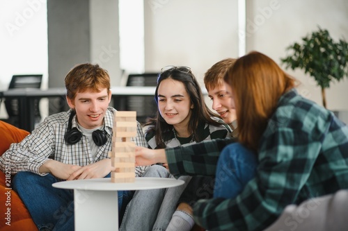 Konstfotografi Friends playing wooden block tower game jenga at home