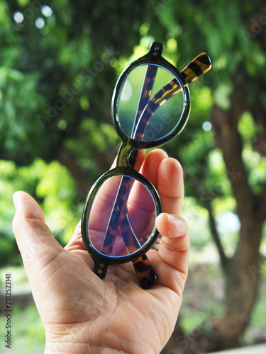 notebook and glasses with headphones on table green garden backgroud