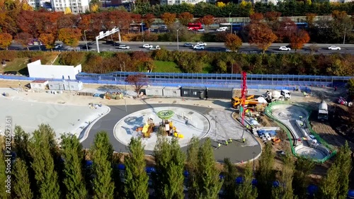 Urban park and playground under construction with workers, machinery and newly developed recreation areas, showing public infrastructure, landscaping and city improvement.