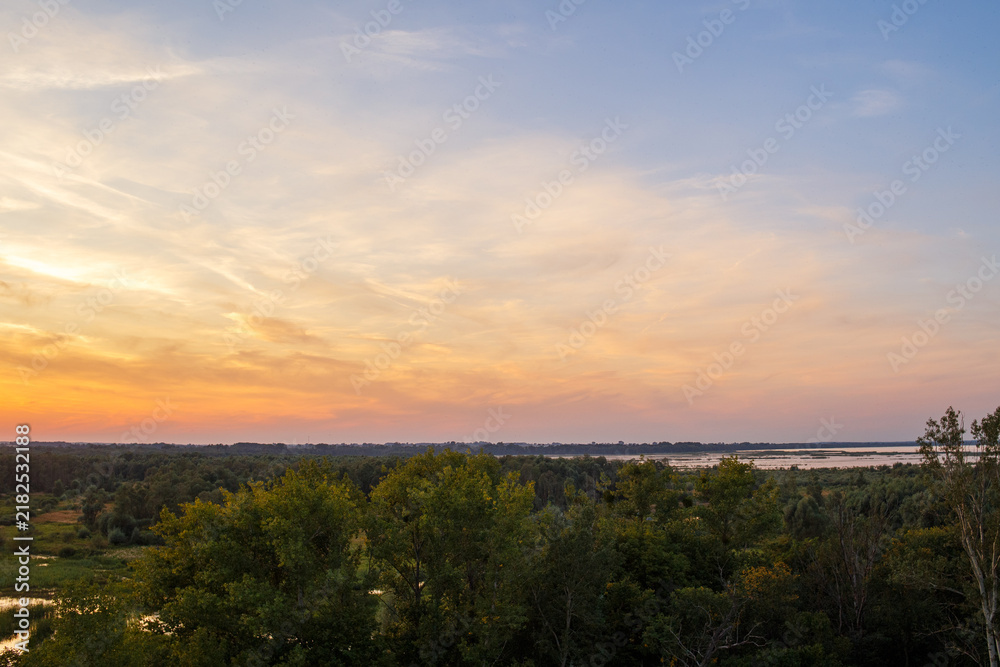 Fototapeta premium Colorful sunset over green valley with lakes and wetlands