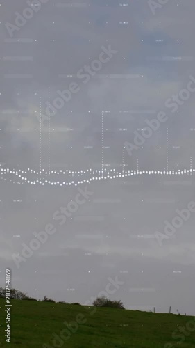 Wind turbine on grassy hill with sound wave animation over cloudy sky